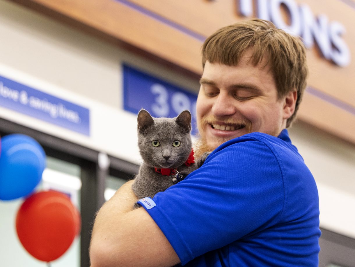 A PetSmart employee holds a cat in his arms