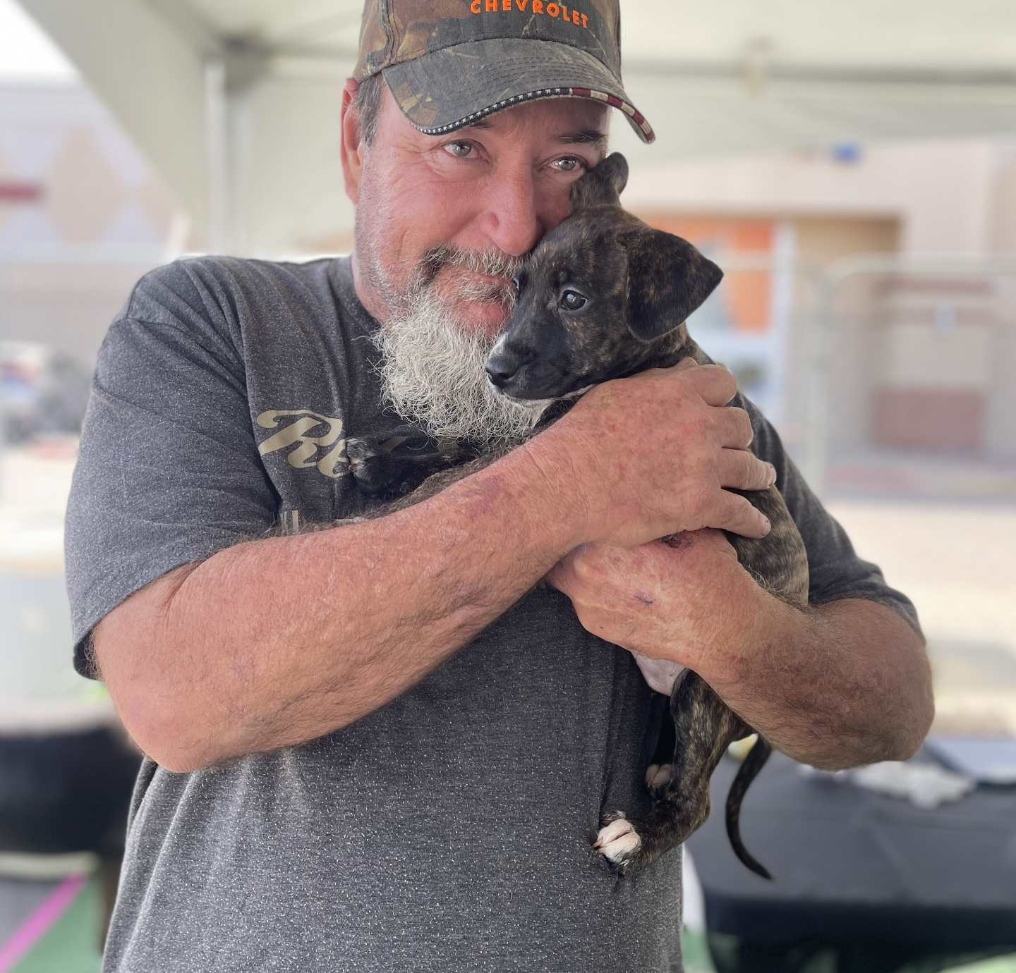 man cuddles puppy he's holding at an adoption event