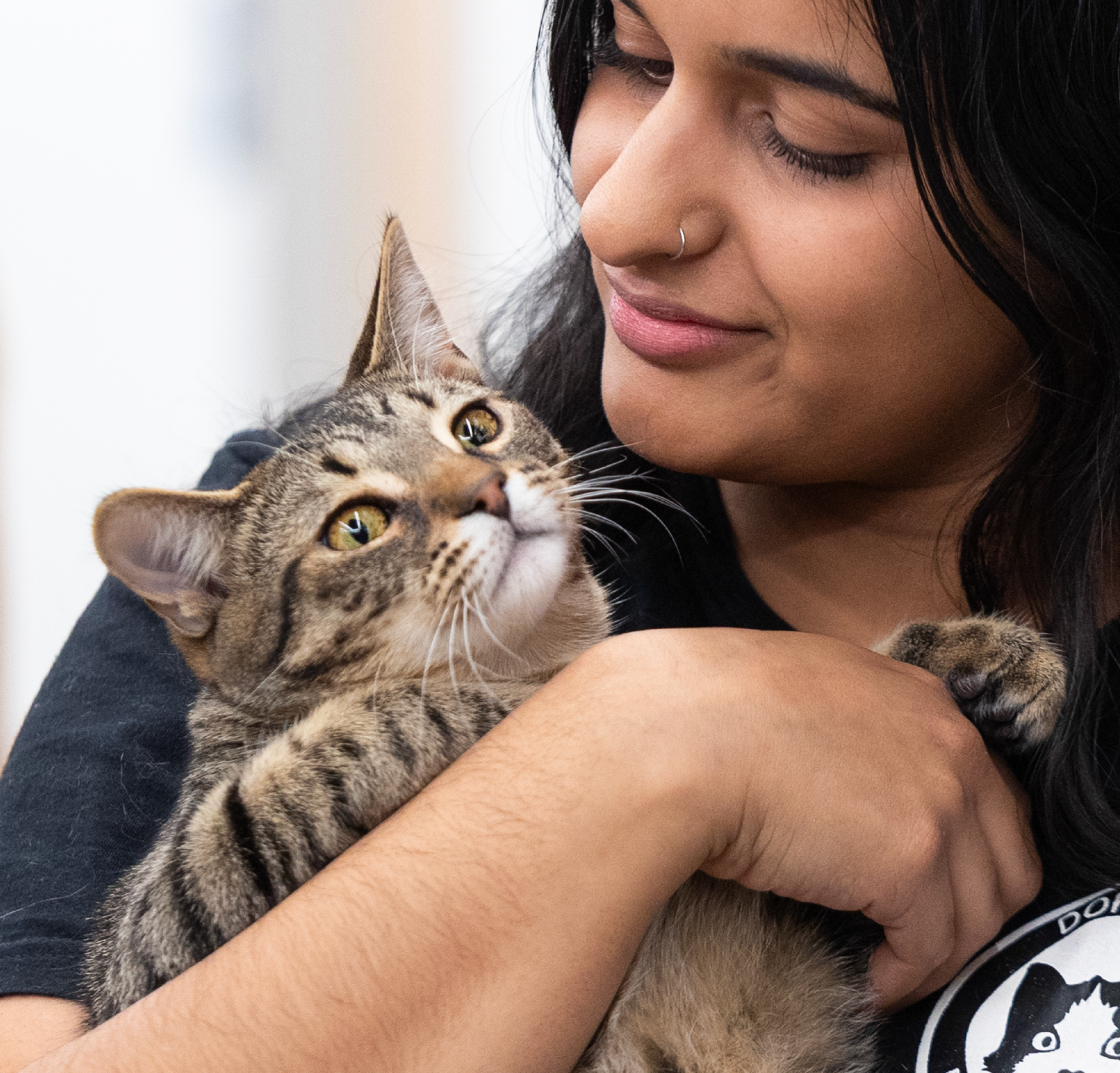 Woman looks at cat she's holding in her arms