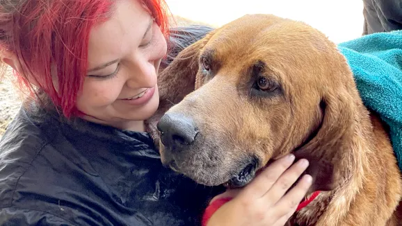 woman with red hair cuddles a big floppy eared dog