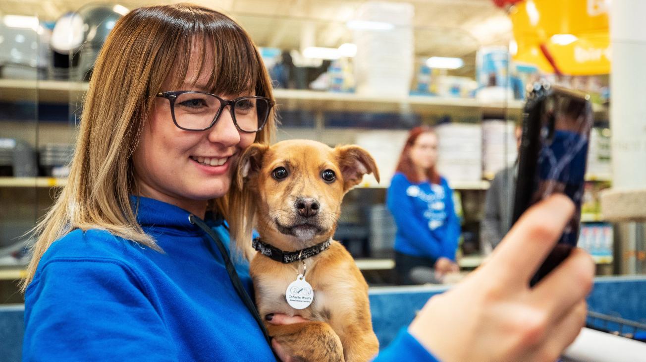 woman taking a picture with a small dog